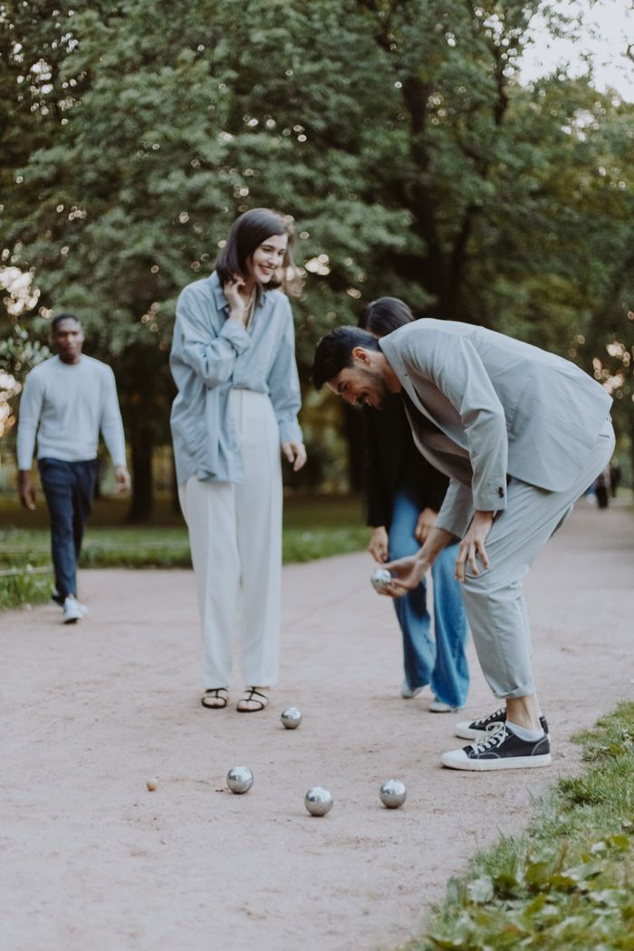 services-01 Friends enjoy a game of boules in a serene green park, having fun and socializing outdoors.