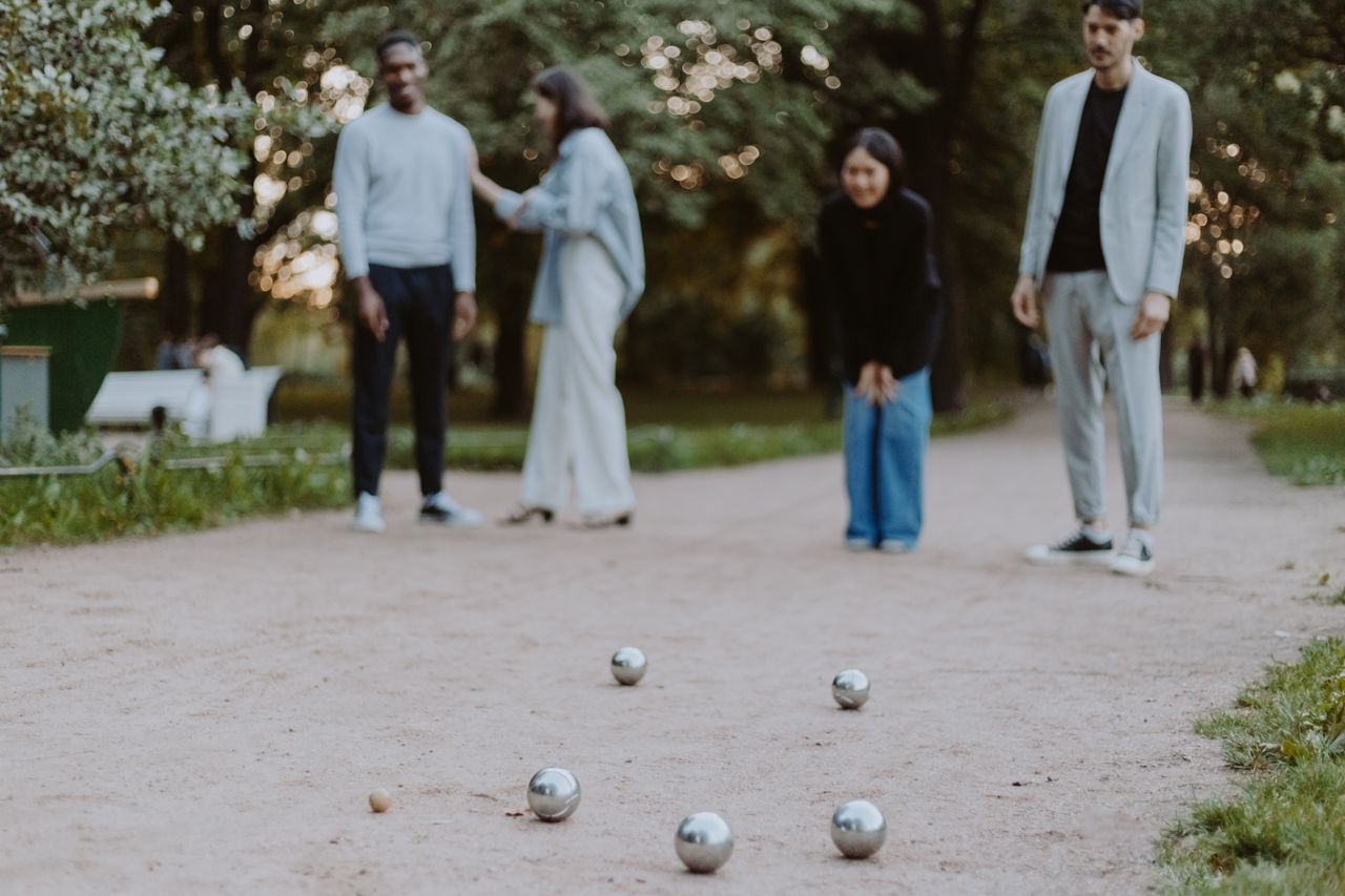 Friends enjoy a lively game of petanque in a scenic park, embracing outdoor fun and togetherness.