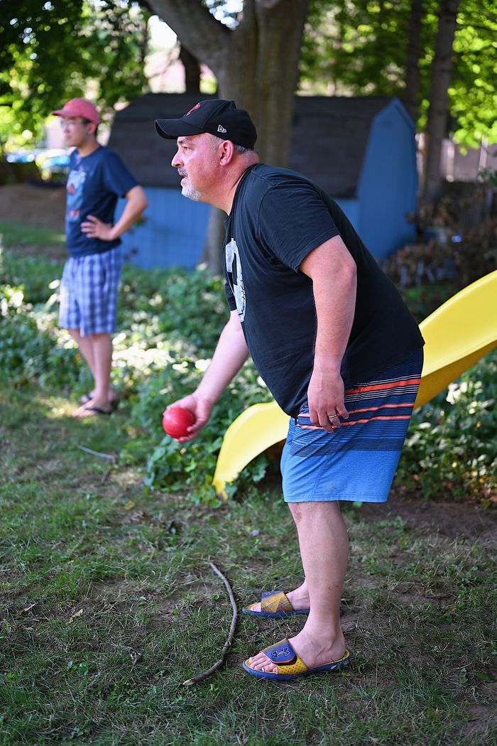 services-02 Two men enjoying a game of bocce in a sunny backyard setting.